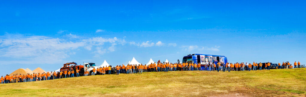 A panorama of Ditch Witch employees stand in a line at the top of a hill.